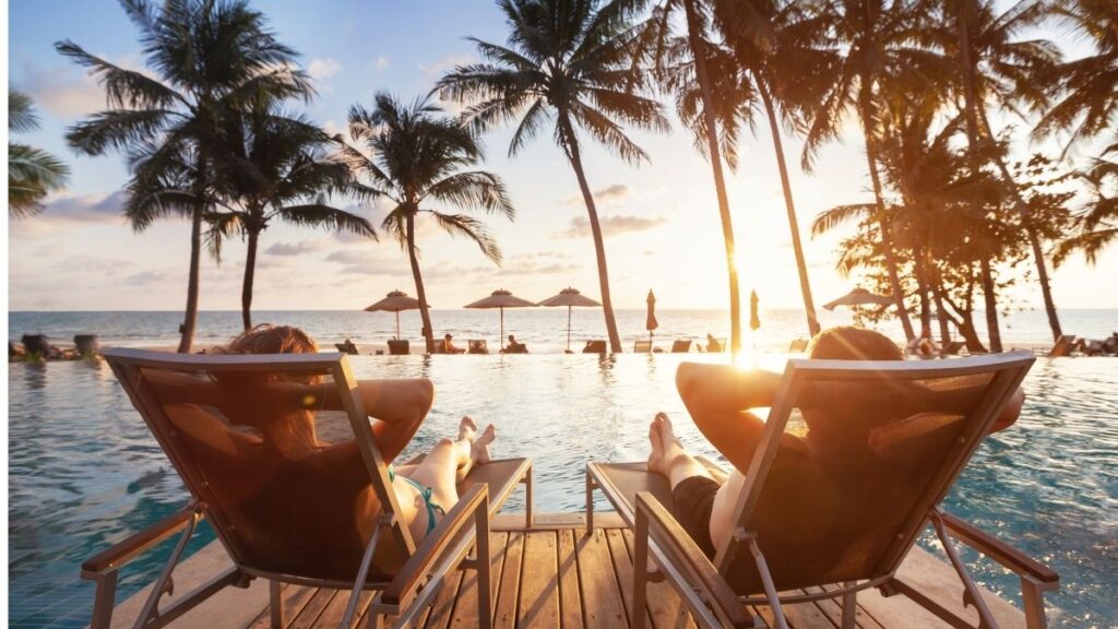 a couple of people sitting in chairs by a pool