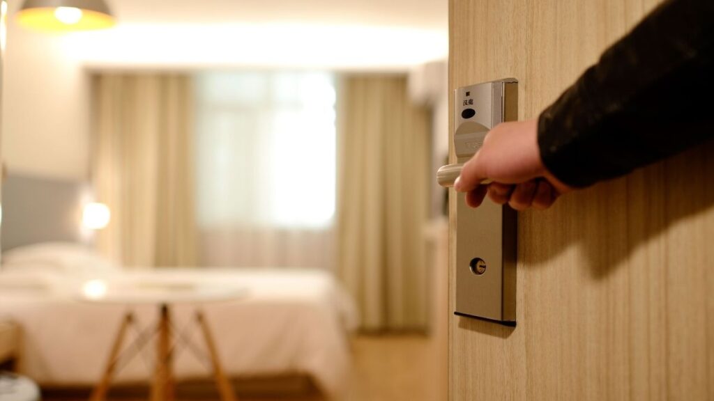 Uma mão abrindo a porta de um quarto de hotel